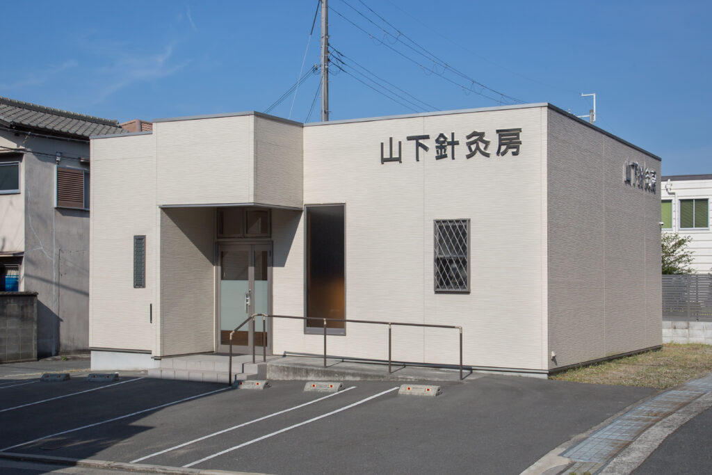 山下針灸房の外観。白い外壁に大きく院名が掲げられ、晴れた空の下で駐車スペースと入口が分かる写真|兵庫県姫路市の妊活・マタニティ鍼灸専門鍼灸院